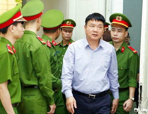 Dinh La Thang, center, is being led out of a court room in Hanoi, Vietnam, Thursday, March 29, 2018. Thang was sentenced to 18 years in prison after being convicted of deliberately violating economic management regulations causing losses of millions of dollars to the state when he headed state oil giant PetroVietnam at the end of the week-long trial Thursday. (Vietnam News Agency Photo via AP)
