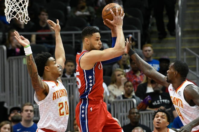 Sixers guard Ben Simmons, center, looks to pass as Hawks forward John Collins, left, and center Dewayne Dedmon, right, defend during Friday's game in Atlanta. [JOHN AMIS/THE ASSOCIATED PRESS]