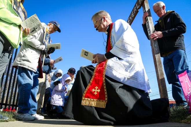 Father William Korte of Jefferson City kneels during the Stations of the Cross as part of a Good Friday abortion protest outside of Planned Parenthood in Columbia. About 60 protesters went through the Stations of the Cross, while about a dozen counter-protesters stood nearby. [Hunter Dyke/Tribune]