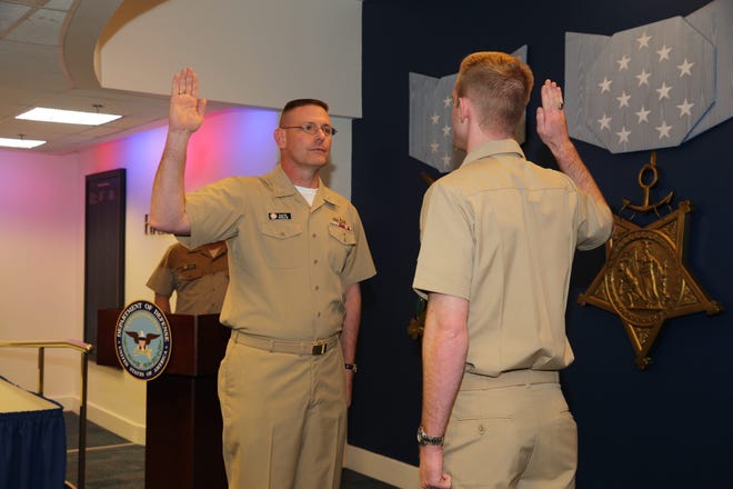 SUPPLIED PHOTO

Capt. Dave Welch repeats the oath of office from his son, Lt. j.g. Benjamin Welch, during his promotion to rear admiral (lower half) in the Hall of Heroes at the Pentagon recently.
