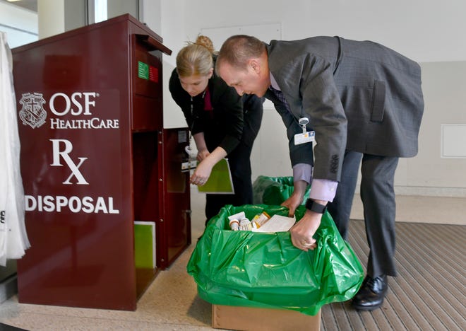 DAVID ZALAZNIK/JOURNAL STAR OSF HealthCare senior vice president of Pharmacy Services Jerry Storm and certified pharmacy technician Megan Behme pull a full container from the medical drug disposal receptacle Friday at the entrance to the hospital. The disposal site is one of two at the hospital and OSF HealthCare plans to place the boxes at each of the hospitals in the system.