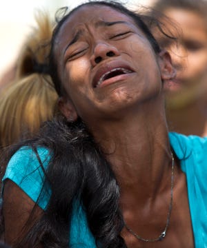A relative grieves during the funeral of Alirio Duran, 25, at the Municipal Cemetery of Valencia, Venezuela, Friday, March 30, 2018. Weeping relatives arrived at the central cemetery on Friday carrying the caskets of many of the 68 victims who were killed in a police station fire to place them in a freshly dug mass tomb. Cemetery workers said they were prepared to bury at least 32 people two days after the blaze in three-deep graves separated by a layer of cinderblock. (AP Photo/Ariana Cubillos)