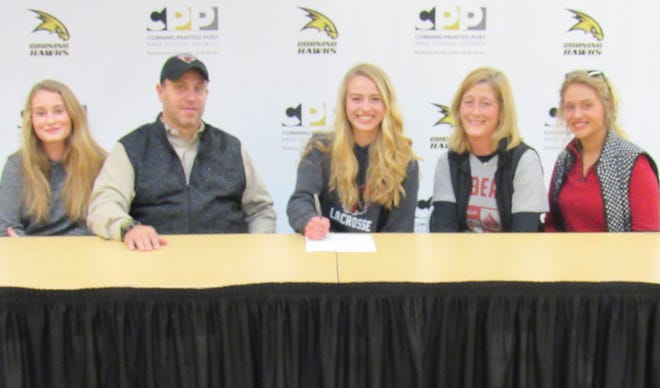 Kelsey Simmons (center) signs her letter of intent to attend Division II Roberts Wesleyan College on Thursday at Corning-Painted Post High School with her family at her side. [TOM PASSMORE/THE LEADER]
