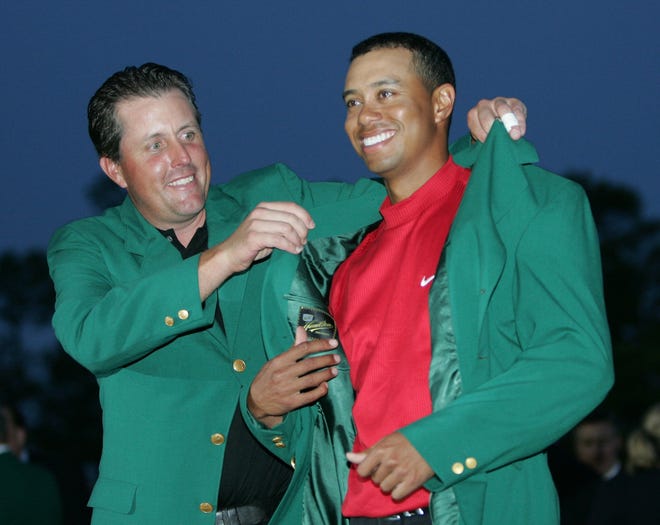 Tiger Woods (right) gets the green jacket for winning the 2005 Masters from defending champion Phil Mickelson. The two players combined to win half of the 14 Masters played from 1997-2010, and are entering next week's tournament on late-career surges. [AP Photo/Morry Gash, File]