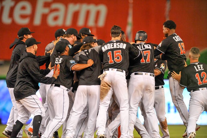 Miami Marlins celebrate after Miguel Rojas hits an RBI single in the 17th inning of a baseball game against the Chicago Cubs, in Miami Saturday March 31, 2018. Marlins won 2-1. (AP Photo/Gaston De Cardenas)