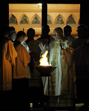 Auxiliary Bishop Robert Evans begins the Easter Vigil Saturday at the Cathedral of Saints Peter and Paul in Providence. [The Providence Journal / Glenn Osmundson]