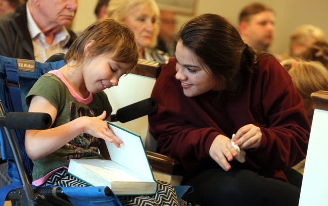 From left, Gracy Jones, 11, and Sydney Patterson, 15, look at a hymnal book during worship at South Mountain Bluegrass Church in Casar. [Brittany Randolph/The Star]