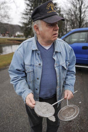 On Wednesday, April 4, 2018 Charles Hamberger holds two examples of memorial markers which were taken from the veterans memorial in Tannersville. [KEITH R. STEVENSON/POCONO RECORD]