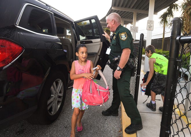Sarasota County Sheriff's Office deputy Sean O'Brien greets kindergartner Makailyn Brown at Lakeview Elementary School during student drop-off on Wednesday morning. [Herald-Tribune staff photo / Dan Wagner]