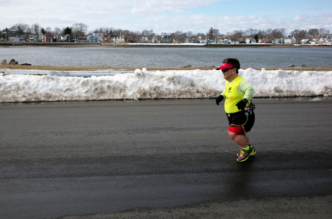 In this Thursday, March 15, 2018, photo, marathon runner John Young, of Salem, Mass., makes his way along a training route in Salem. Young was born with dwarfism, but that hasn't stopped him from conquering multiple marathons and triathlons. While most marathoners take about 35,000 steps to reach the finish line, Young uses about 80,000. (AP Photo/Steven Senne)