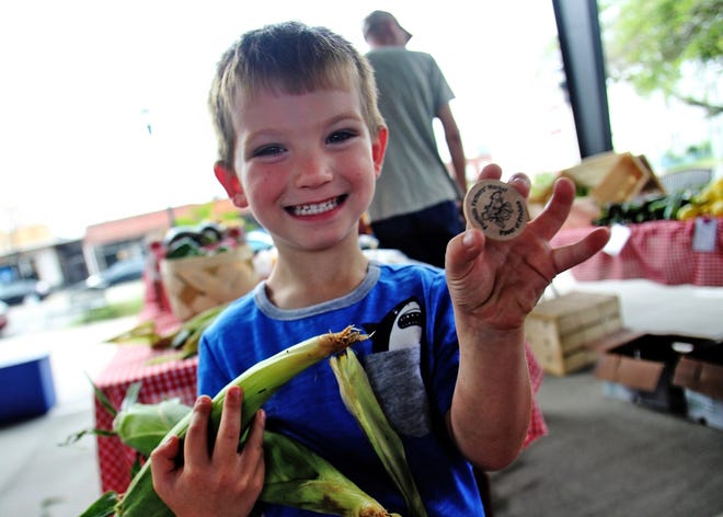 Jaxon Watts shows off a 'Pop' coin he exchanged for ears of corn at the Farmers' Market last year. [Star file photo]