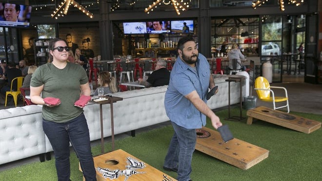Kristyn Masaad and Ryan Perez toss bean bags during a work team-building exercise hosted at Culinary Dropout in the Domain Northside last month.