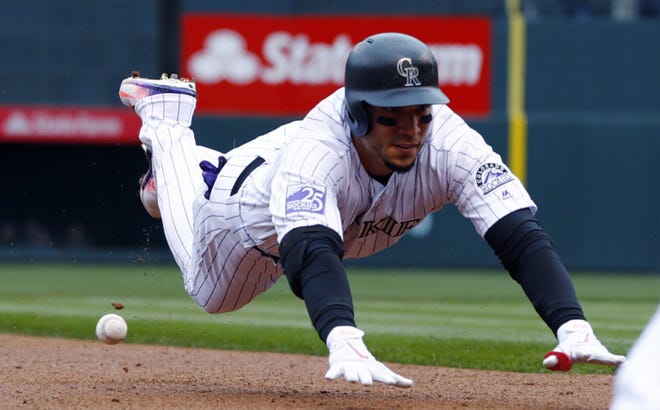 Colorado Rockies' Carlos Gonzalez dives into third base with an RBI-triple in the first inning of a game against the Atlanta Braves, Friday in Denver. (AP Photo/David Zalubowski)