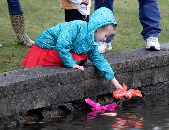 Jalynn Hinton, 6, of East Liverpool, prepares to drop a floating lit candle into the lake in remembrance of a family member at the sixth annual Light Up the Lakes on the campus of the University of Mount Union Friday night.