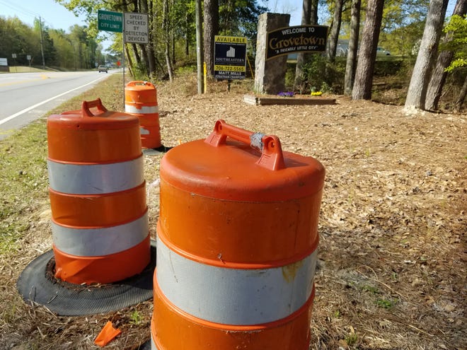 Orange traffic barrels and a real-estate sign advertising available property – two familiar sights around Columbia County – stand near a sign marking Grovetown's city limits. [JOE HOTCHKISS/THE AUGUSTA CHRONICLE]