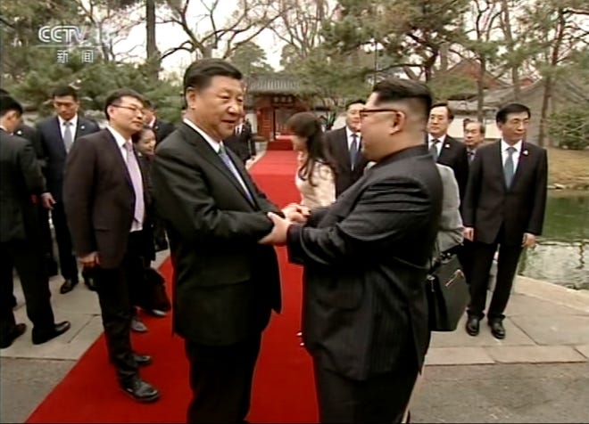 In this image taken from video footage run March 28, by China's CCTV, North Korean leader Kim Jong Un, right, and Chinese counterpart Xi Jinping, left, shake hands in Beijing. [CCTV via AP Video]