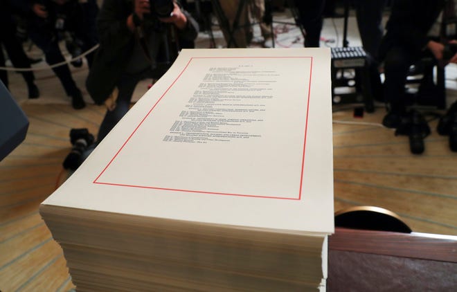 In this March 23, 2018, file photo, a copy of the $1.3 trillion spending bill is stacked on a table in the Diplomatic Room of the White House in Washington. A new analysis says President Donald Trump's tax cuts and last month's big spending bill will send the federal deficit toward $1 trillion. The Congressional Budget Office says tax and spending bills will push the deficit to $804 billion this year and nearly $1 trillion for 2019. (AP Photo/Pablo Martinez Monsivais)