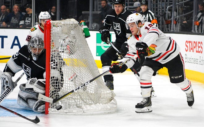 FILE - In this March 3, 2018, file photo, Chicago Blackhawks right wing Alex DeBrincat, right, tries to center the puck behind the net as Los Angeles Kings goalie Jonathan Quick defends during an NHL hockey game in Los Angeles. Blackhawks general manager Stan Bowman has said the team’s top priority is keeping the young players who have impressed this season, including rookie DeBrincat. (AP Photo/Michael Owen Baker, File)