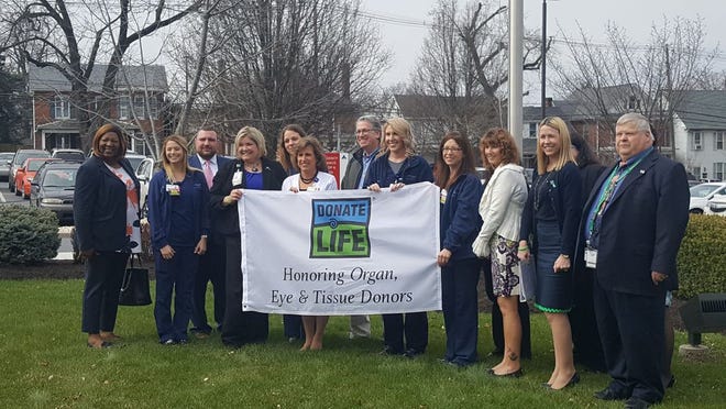 A group of representatives from Summit Health, the Center for Organ Recovery & Education and community members pose before a flag-raising ceremony to commemorate National Donate Life Month Wednesday morning at Chambersburg Hospital. ANDREA ROSE/THE RECORD HERALD