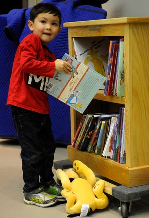 Jacob Alliman looks up as he puts a book onto his new bookcase, which he received during the Seventh Annual Award Ceremony for the Ashland Bookcase Project on Sunday at Trinity Lutheran Church.