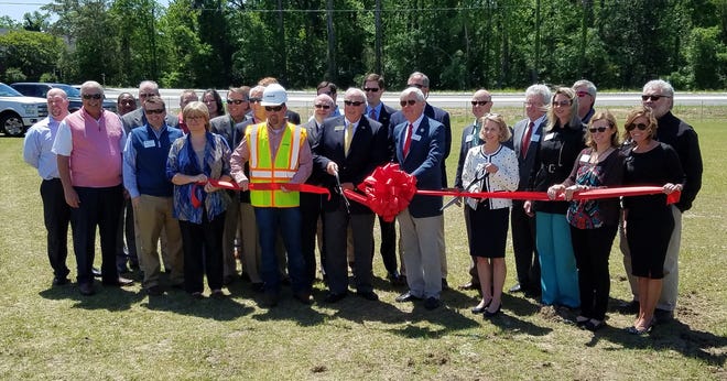 Georgia Department of Transportation District 12 Commissioner Don Grantham (center, yellow tie) joined other local and state officials in cutting the ribbon Tuesday to officially mark the completion of the River Watch Parkway extension in Columbia County. Standing to the right of Grantham is Columbia County Board of Commissioners Chairman Ron Cross. To the right of Cross is Executive Director Tammy Shepherd of the Columbia County Chamber of Commerce. [JOE HOTCHKISS/THE AUGUSTA CHRONICLE]