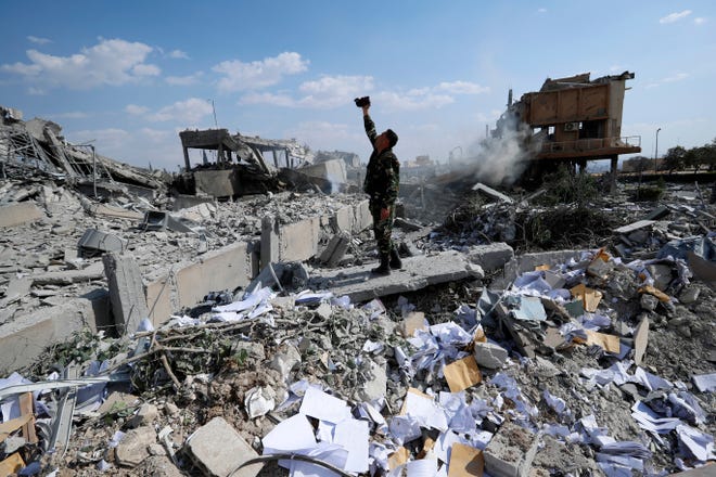 A Syrian soldier films the damage of the Syrian Scientific Research Center Saturday which was attacked by U.S., British and French military strikes to punish President Bashar Assad for suspected chemical attack against civilians, in Barzeh, near Damascus, Syria. [Hassan Ammar/The Associated Press]