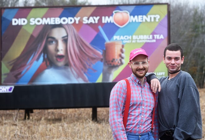 Emmett Soldati, graphic artist and owner of Teatotaller Tea House, left, and employee and model, Michael Cummings, stand in front of the latest billboard creation on West High Street in Somersworth. 
[Deb Cram/Fosters.com]