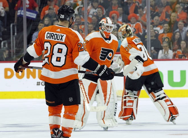 As Philadelphia Flyers' Captain Claude Giroux watches, goalie Brian Elliott, center, skates off and is replaced by Michal Neuvirth during the second period in Game 4 of an NHL first-round hockey playoff series against the Pittsburgh Penguins, Wednesday, April 18, 2018, in Philadelphia. (AP Photo/Tom Mihalek)