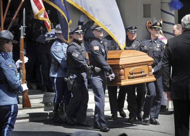Yarmouth officers and Massachusetts State Police troopers carry the casket of Yarmouth K-9 Officer Sean Gannon to the hearse after a funeral service at St. Pius X Roman Catholic Church on Wednesday. [The Cape Cod Times via AP / Ron Schloerb]