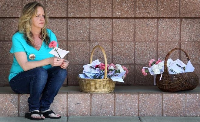 Jamie Fraley's mother, Kim Fraley, sits outside the Gaston County Police Department passing out flowers and cards in this 2013 file photo. [John Clark/The Gaston Gazette]