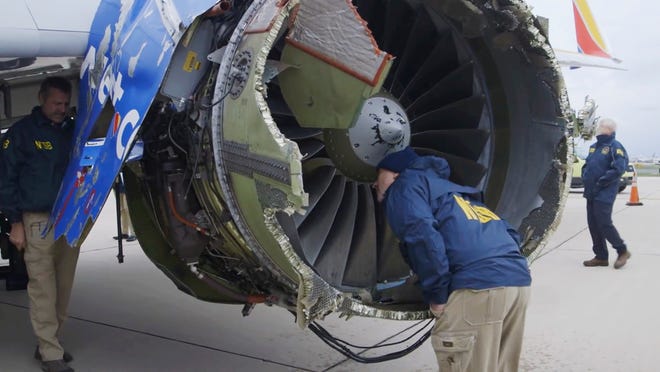 In this Tuesday, April 17, 2018 frame from video, a National Transportation Safety Board investigator examines damage to the engine of the Southwest Airlines plane that made an emergency landing at Philadelphia International Airport in Philadelphia. A preliminary examination of the blown jet engine of the Southwest Airlines plane that set off a terrifying chain of events and left a businesswoman hanging half outside a shattered window showed evidence of "metal fatigue," according to the National Transportation Safety Board.