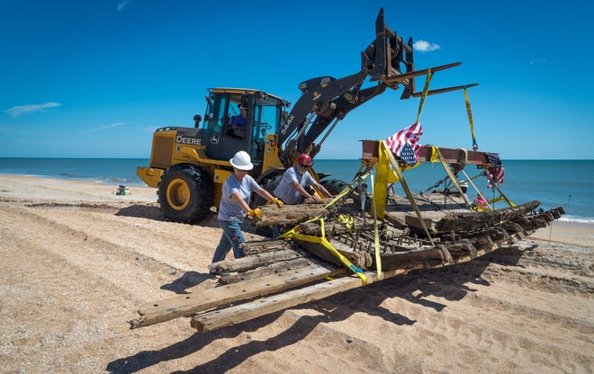 Workers use a front end loader to move a 48-foot section of a wooden hull of a sailing ship that washed ashore on south Ponte Vedra Beach in March from the beach on Thursday. The hull of ship is estimated to date from the mid 1800s. [PETER WILLOTT/THE RECORD]