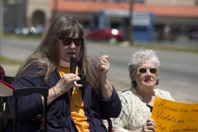 Jo Shaffer holds up a Columbine Cross during a demonstration remembering the victims Columbine High School massacre that happened 19 years ago. Shaffer is from Colorado and remembers the panic her community felt as news came that friends and loved ones were killed in the school shooting. [JOSHUA BOUCHER/THE NEWS HERALD]