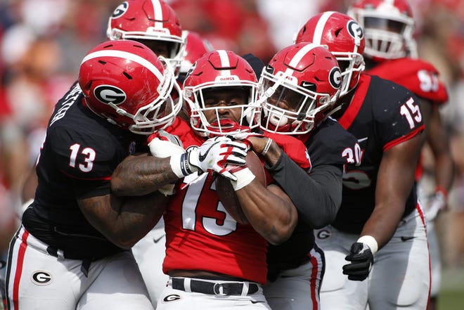 Georgia tailback Elijah Holyfield (13) is stoped by Georgia defensive end Jonathan Ledbetter (13) and Georgia inside linebacker Tae Crowder (30) during Saturday's G-Day game. (Photo/Joshua L. Jones, Athens Banner-Herald)