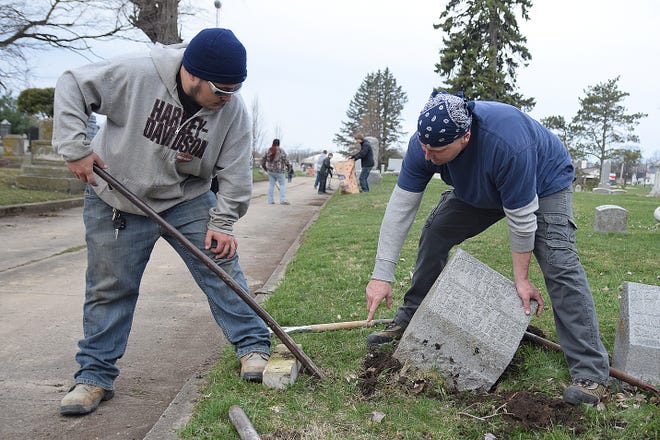 David Dawson and his uncle Mike Dawson straighten leaning tombstones Saturday morning during the Hope Cemetery cleanup day in Galesburg. [BILL NICE/The Register-Mail]