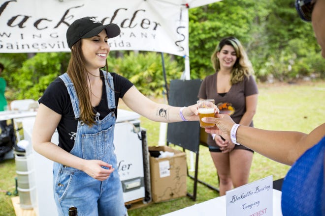 Sara Sieger hands out beer from Blackadder Brewing Company during the Hogtown Craft Beer Fest at the Alachua County Fairgrounds Saturday. [Lauren Bacho/Staff photographer]