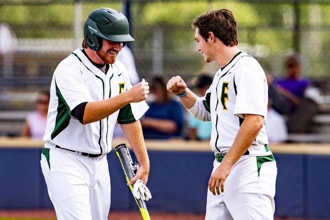 Forest's Tyler Waddell, left, fist bumps teammate Grant Grodi after scoring a run during the Wildcats' 16-0 win against Gainesville High at the College of Central Florida on Tuesday. [Lauren Bacho/Staff photographer]