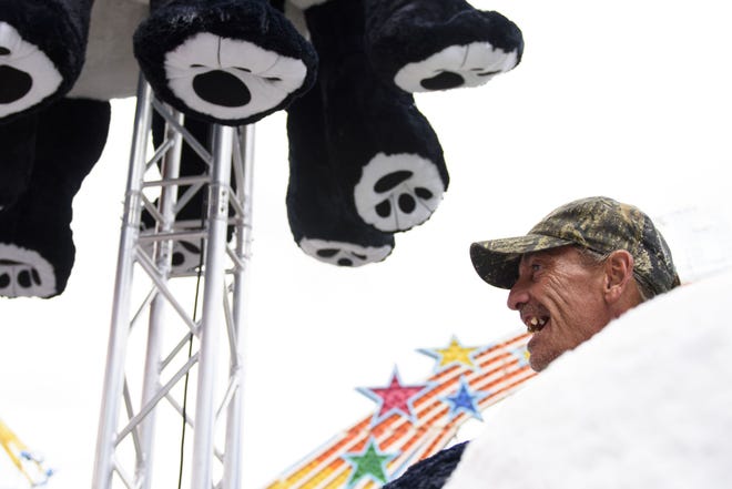 Butch Eaton hangs giant stuffed panda toys at a game at the Fort Bragg Fairgrounds on Wednesday. The fair opens Thursday and continues through May 13. [Melissa Sue Gerrits/The Fayetteville Observer]