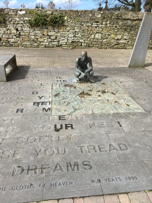 A statue seems to consider the words of W.B. Yeats etched into the pavement outside the churchyard at Drumcliffe, Ireland, where the poet's remains are interred. [PHOTOS BY TONY SIMMONS/THE NEWS HERALD]