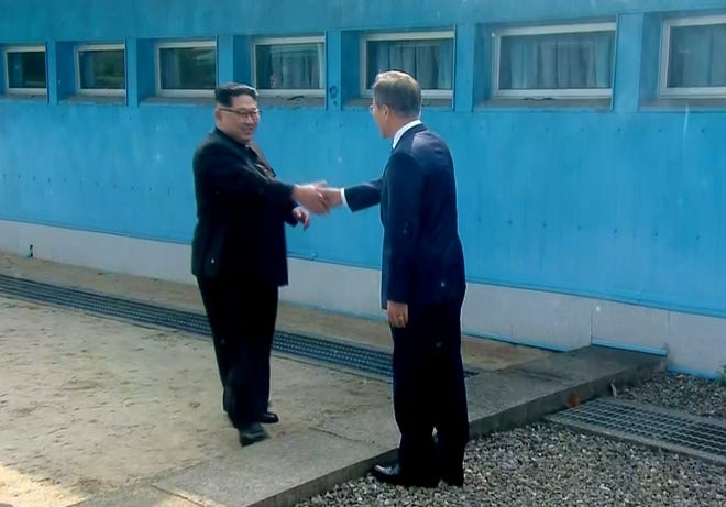 North Korean leader Kim Jong Un (left) shakes hands with South Korean President Moon Jae-in as Kim arrives at Panmunjom for their historic face-to-face talks today. [Korea Broadcasting System via AP]