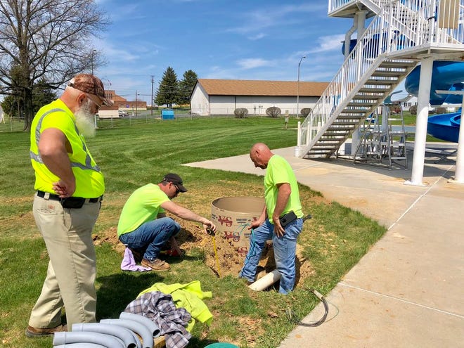 Borough maintenance workers Chris Eyler, left, Jamie Shindledecker and Jody Sanders work on the installation of the new LED lights at Northside Pool Monday afternoon. JOHN IRWIN/ THE RECORD HERALD