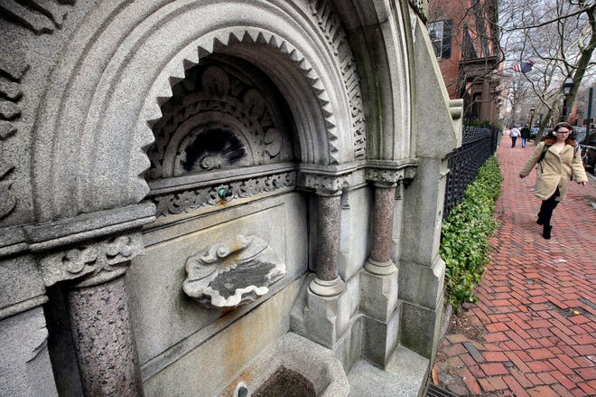 In this Tuesday, April 17, 2018, a person walks past the granite fountain in front of the Providence Athenaeum library. Legend has it that anyone who sips from the 145-year-old public drinking fountain is destined to return. [AP Photo/Steven Senne]