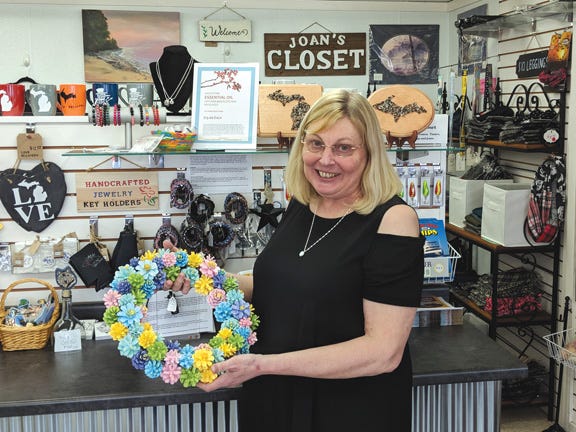 Sault Boutique & Artisan Market owner Joan Roney hold's a colorful pinecone reef handcrafted by Tricilla Berlin of Brimley. Items such as the wreath are a found aplenty inside the West Portage Avenue store. Fifty vendors across the Upper Peninsula have items for sale in the store.