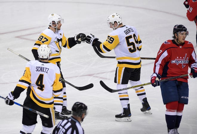 Pittsburgh Penguins center Jake Guentzel (59) celebrates his goal with center Sidney Crosby (87) and defenseman Justin Schultz (4) during the third period in Game 1 of an NHL second-round playoff series as Washington Capitals right wing T.J. Oshie (77) skates away Thursday. The Penguins won 3-2 and the Capitals will try to bounce back after blowing a two-goal lead. [The Associated Press]