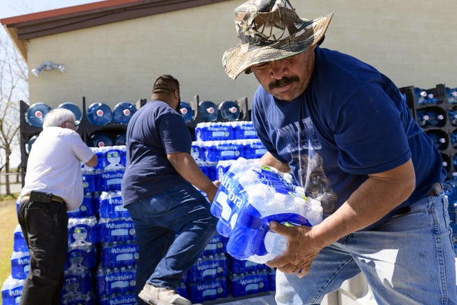 Nicolas Cuevas, right, and others load up plastic water bottles to distribute to members of the Yerington Paiute tribe Friday after their weekly water delivery was left at the tribal border in Yerington, Nevada. Atlantic Richfield, the owner of a abandoned open pit mine nearby, has suspended the normal bottled water deliveries it's been providing neighbors since tests in 2004 confirmed a plume of groundwater contaminated area wells. The move comes two months after federal regulators backed off plans to add the mine to the list of the most toxic U.S. Superfund sites. [Scott Sady/The Associated Press]