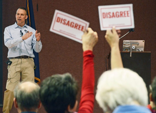 Audience members hold signs reading "DISAGREE" as U.S. Rep. Scott Perry, R-Pa., speaks during a town hall meeting in Red Lion, Pa., last year. Pennsylvanians will settle 21 primary contests for U.S. House seats in the May 15 primary election, the most since 1984, and four candidates are seeking the Democratic nomination to challenge Perry's bid for a fourth term. [AP Photo/Marc Levy, File]