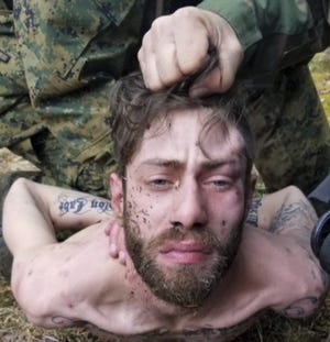 This photo released by the Maine State Police shows an officer holding John Williams for an identification photo as he was being apprehended Saturday, April 28, 2018, in Norridgewock, Maine. Williams was wanted in the fatal shooting of Somerset County Sheriff's Deputy Eugene Cole early Wednesday after the two had an encounter on a darkened road in Norridgewock. Officials said the 29-year-old Madison man also stole Cole's cruiser and robbed a convenience store. (Maine State Police via AP)