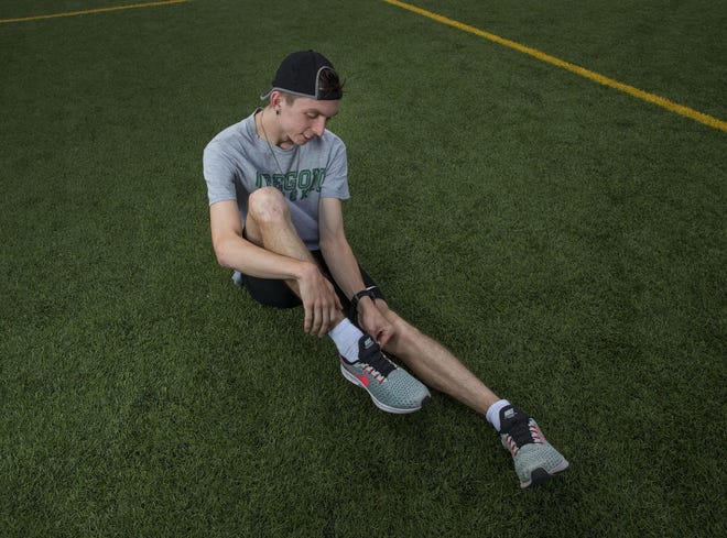 Justin Gallegos, an Oregon club runner with cerebral palsy, who will be running in the Eugene half marathon puts on the prototype shoes he helped test. [Chris Pietsch/The Register-Guard]