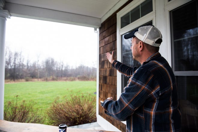 Gabe DeSilva, standing on the porch of his home, points to the area where the proposed warehouse would be constructed in the Town of Hamptonburgh. [KELLY MARSH PHOTOS/FOR THE TIMES HERALD-RECORD]