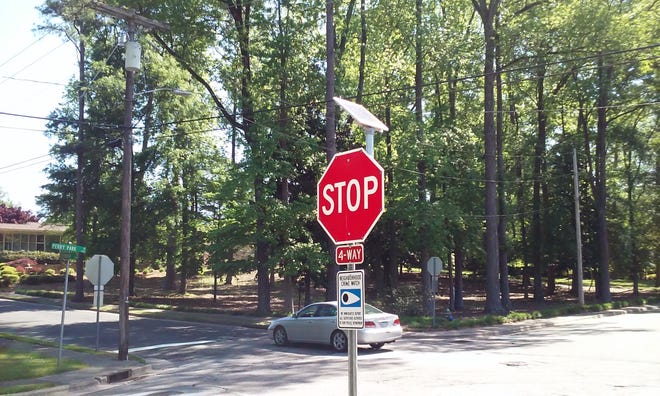 A vehicle passes through the intersection of Perry Park Drive and Greenbriar Road where a new solar-powered stop sign with eight flashing lights has been installed. [EDDIE FITZGERALD / THE FREE PRESS]